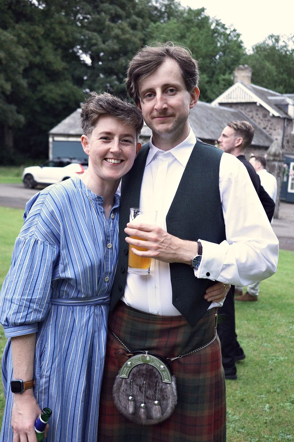 Áine and Paul smiling at the camera, Paul in a kilt holding a pint