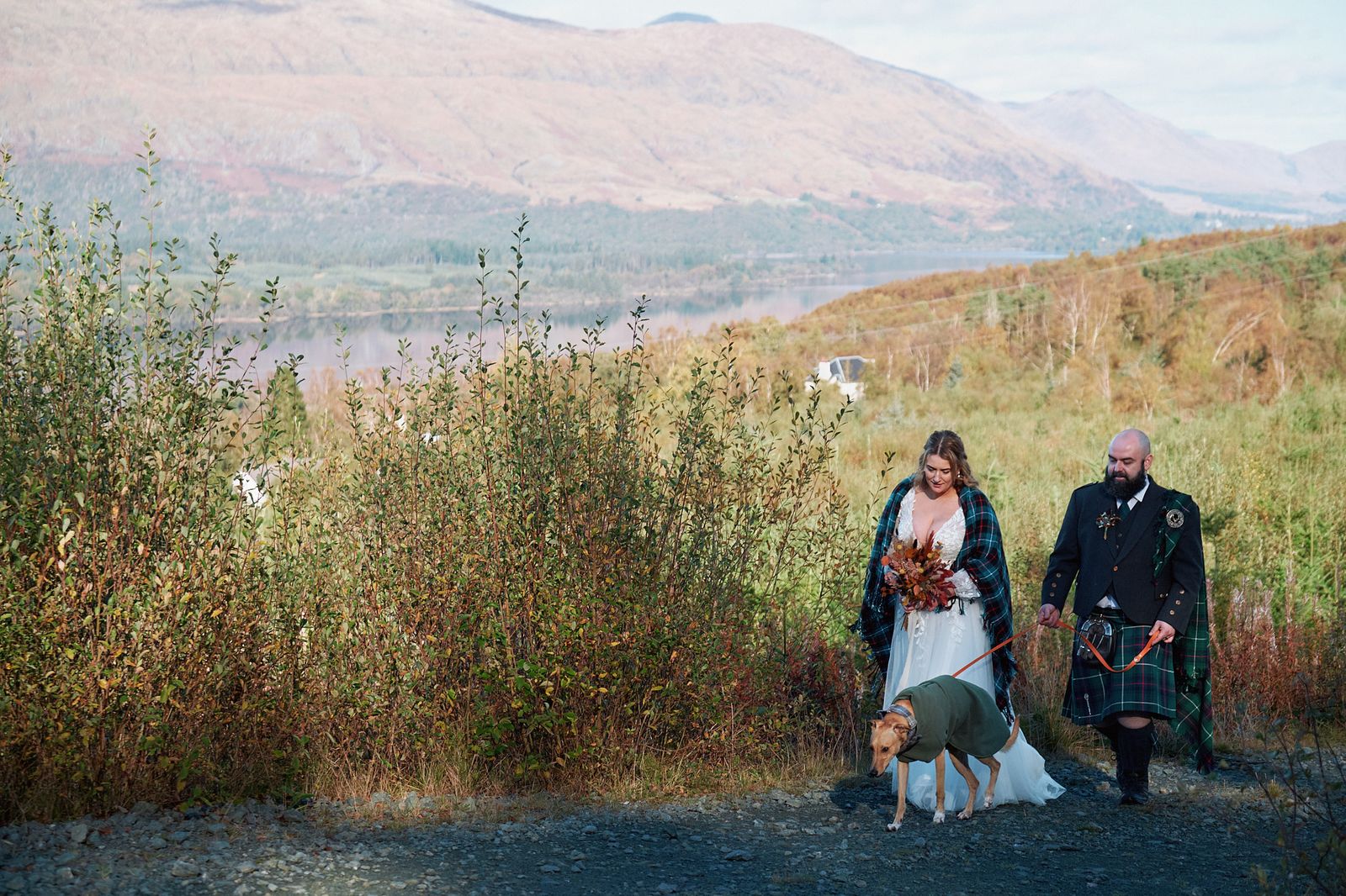A couple and their dog with a view over the hills and loch