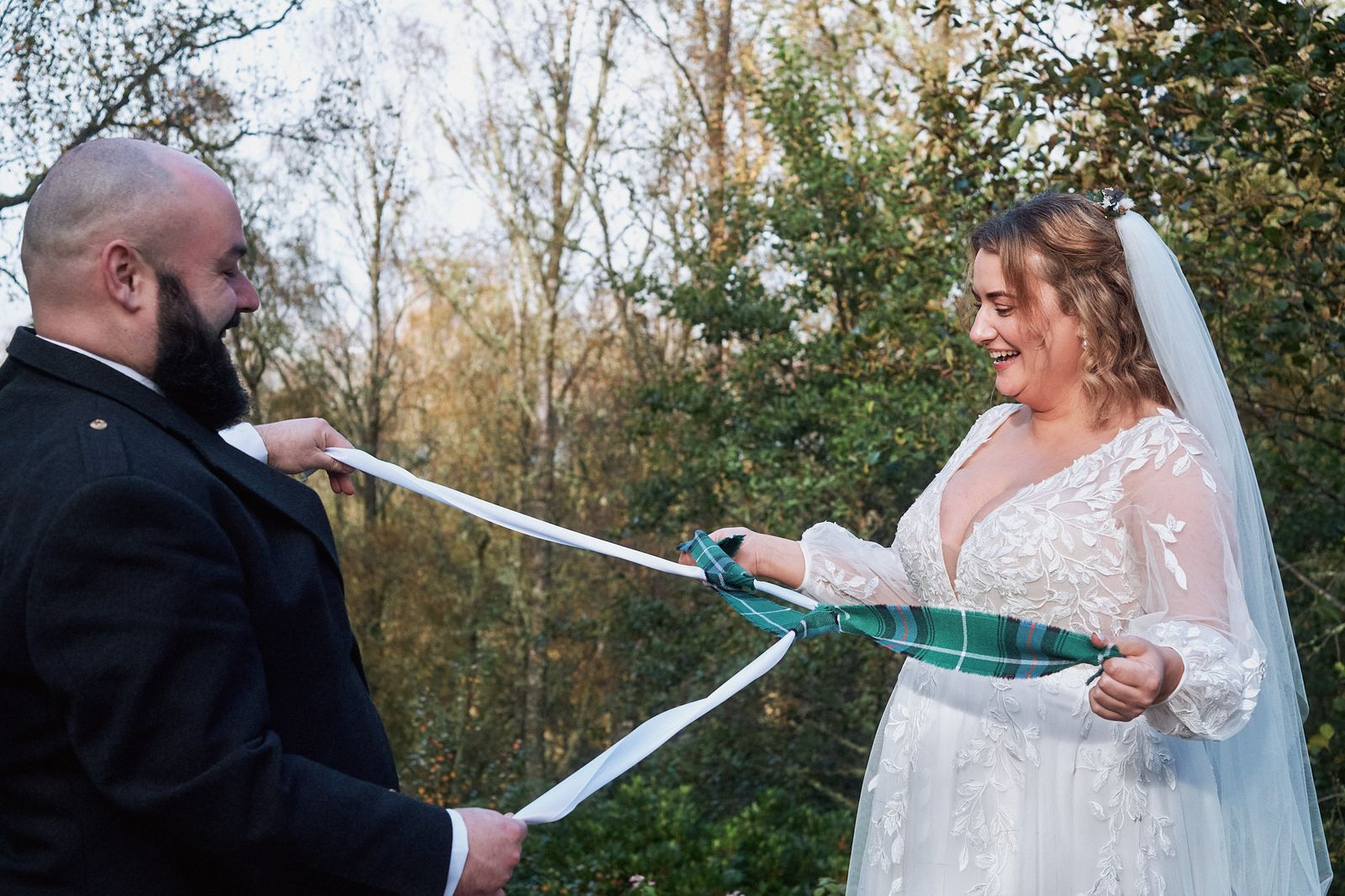 Handfasting with tartan ribbon during an outdoor ceremony