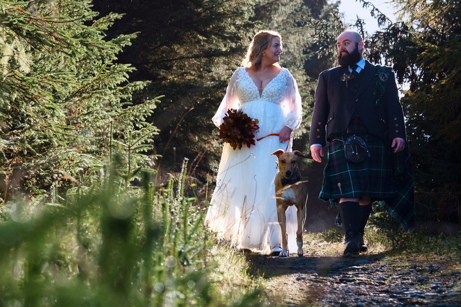 The couple and their dog walking through bracken on a woodland path